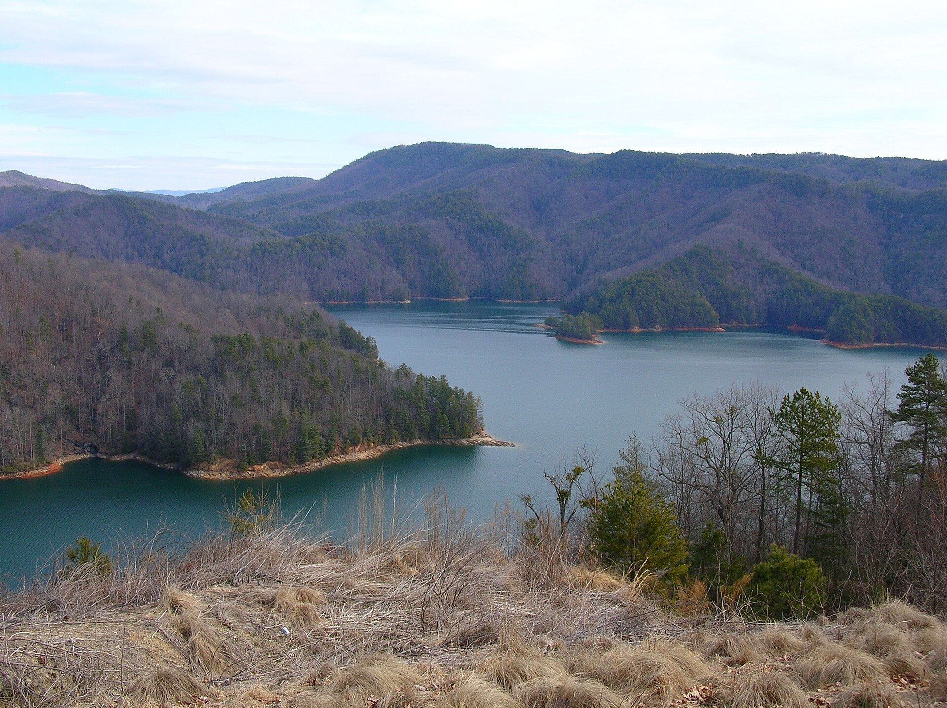 Lake Jocassee from a high overlook: deep green-blue water winding between steep, forested mountain ridges.