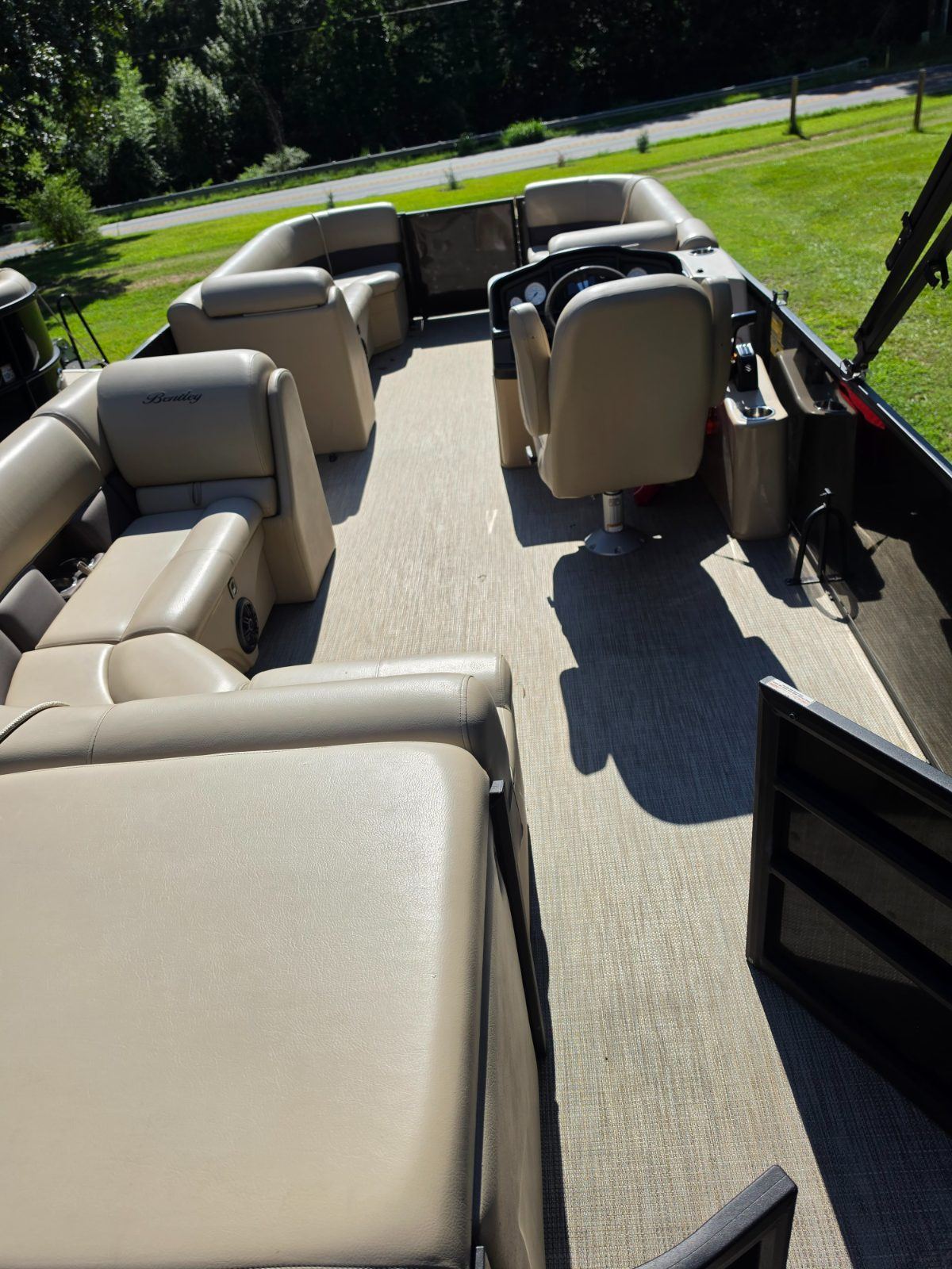 Looking down the length of the tritoon deck: tan wraparound seating, a captain’s chair at the helm, and open floor down the middle.