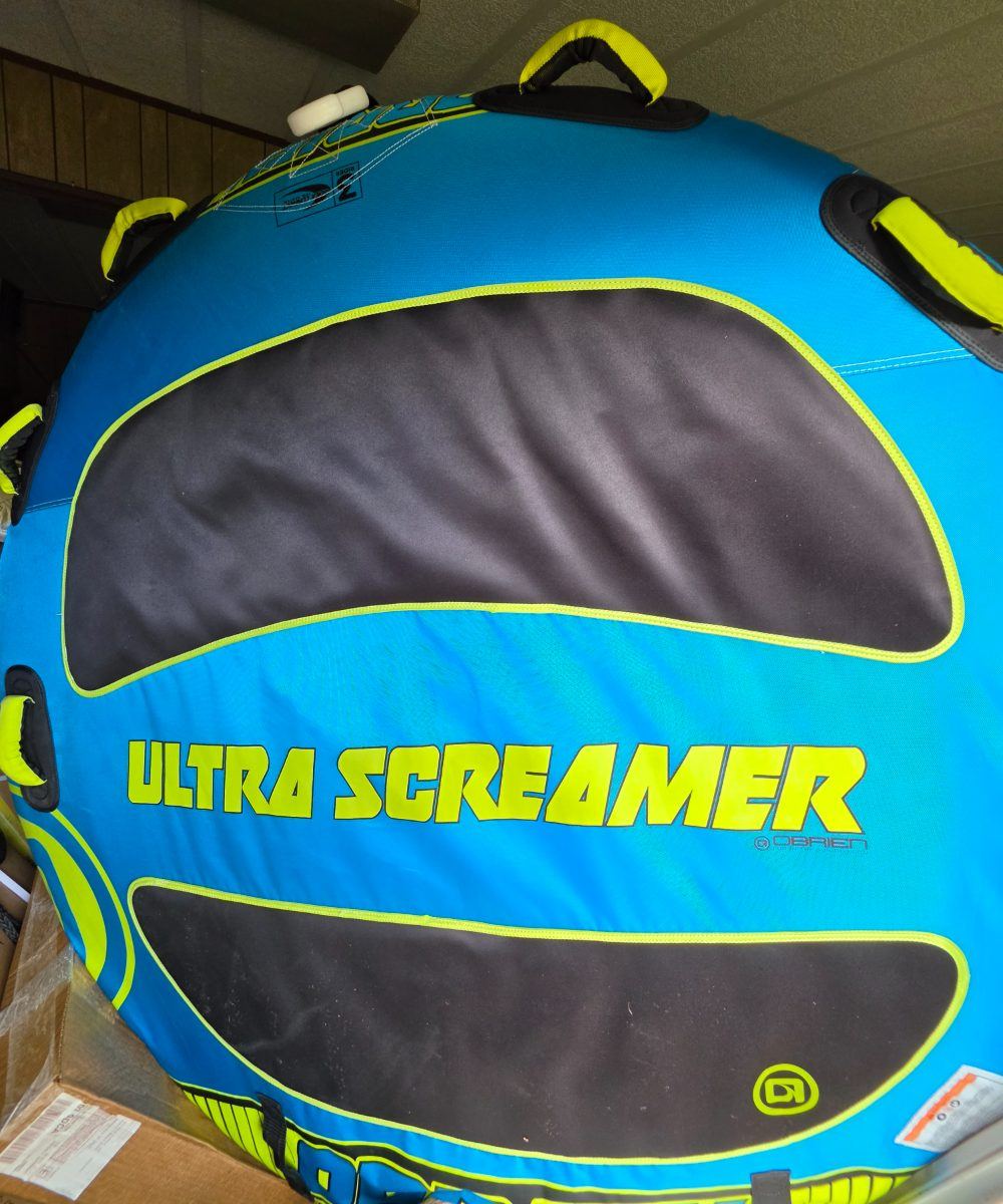 A blue and yellow two-person towable tube with padded handles.